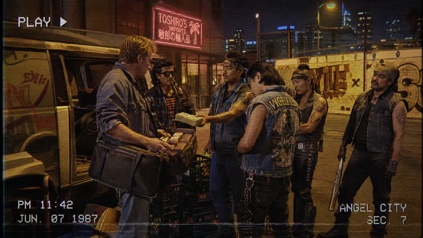 The image shows a group of people, possibly in a city environment, with one individual, presumably a man with a blue shirt, holding a package or object, while others appear to be waiting or looking around. KI-generierte Inhalte können fehlerhaft sein.